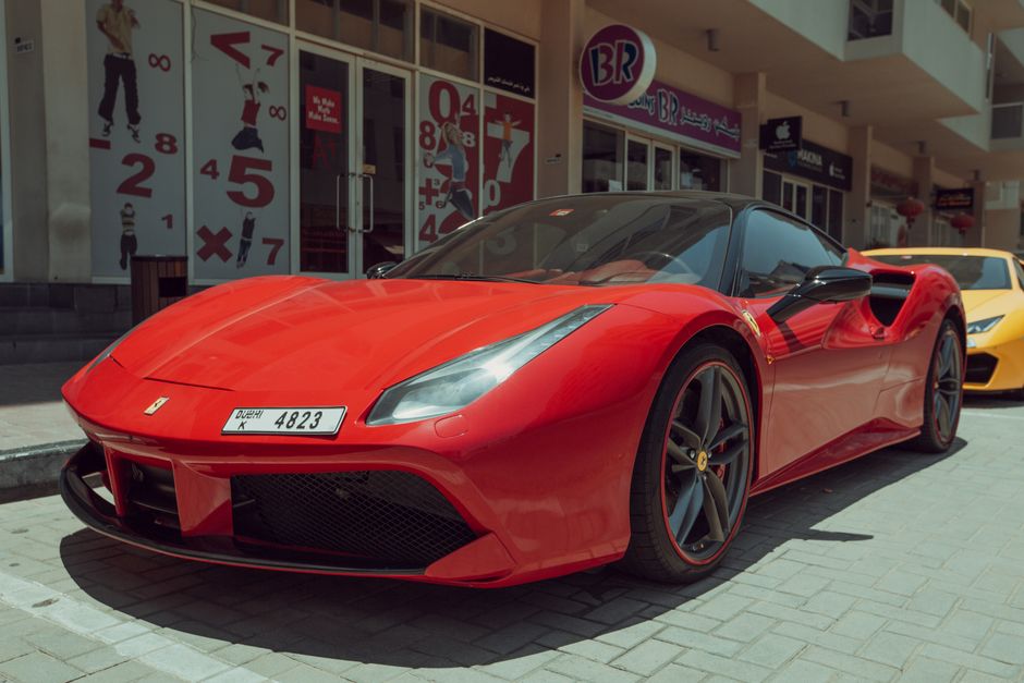 Red Ferrari sports car parked in Dubai, showcasing luxury and style