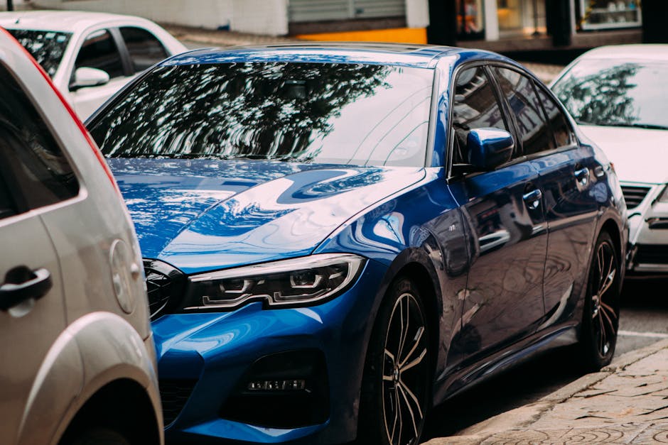 A vibrant blue luxury sedan parked on an urban street among cars